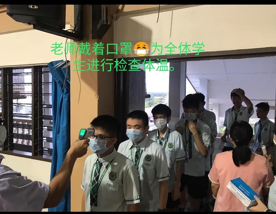 行政老师正为教职员、孩子们进行体温检查。