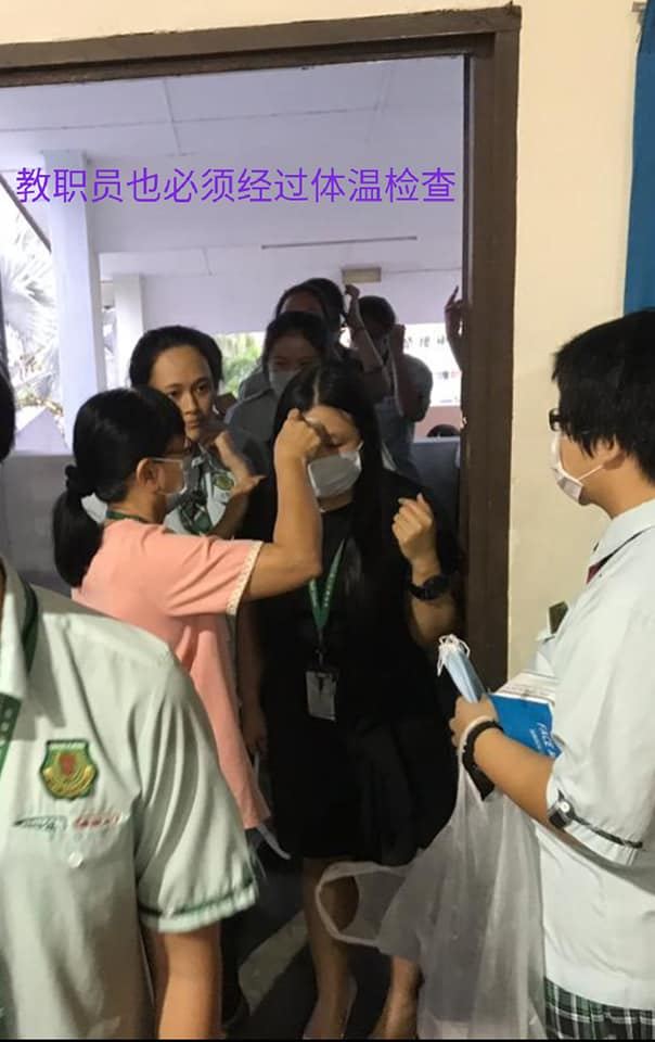 行政老师正为教职员、孩子们进行体温检查。