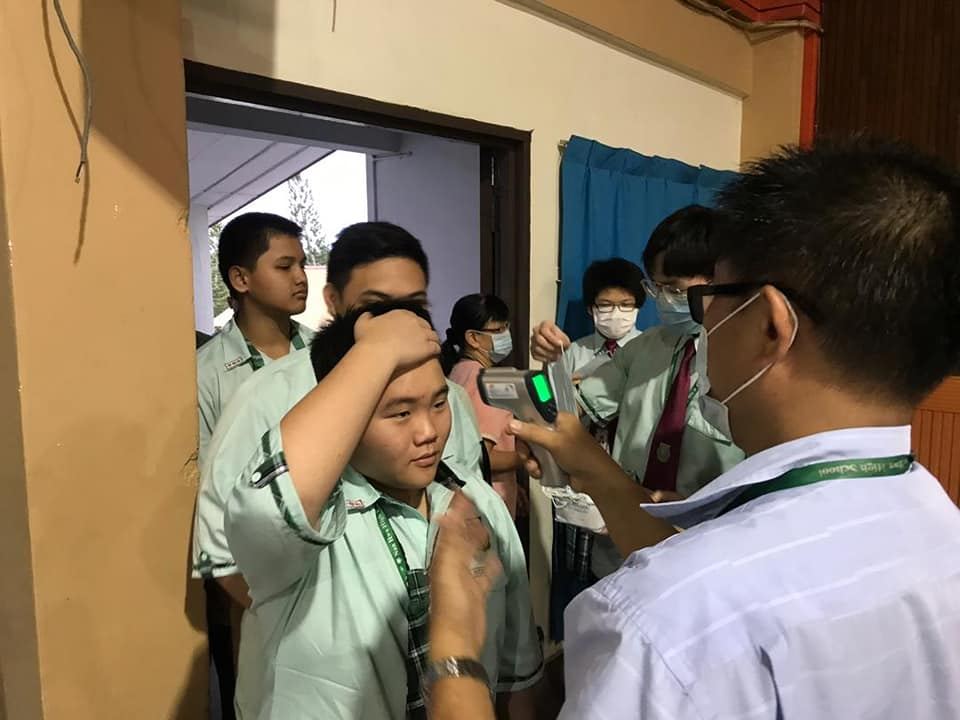 行政老师正为教职员、孩子们进行体温检查。