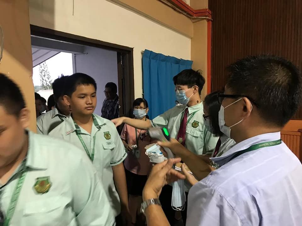 行政老师正为教职员、孩子们进行体温检查。