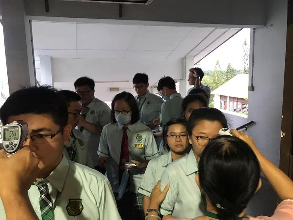 行政老师正为教职员、孩子们进行体温检查。