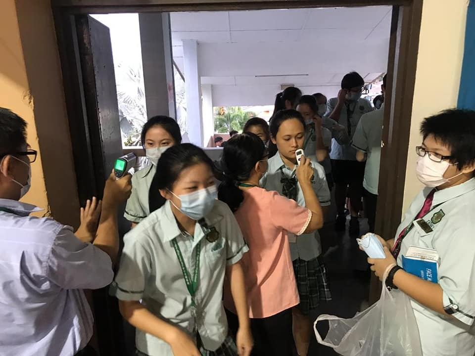 行政老师正为教职员、孩子们进行体温检查。