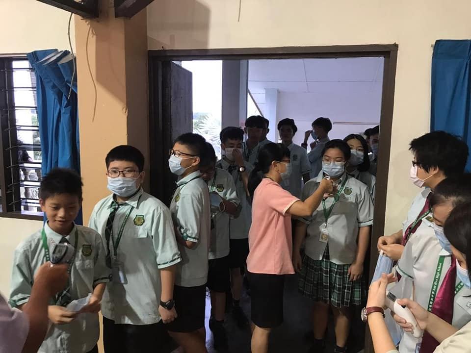 行政老师正为教职员、孩子们进行体温检查。