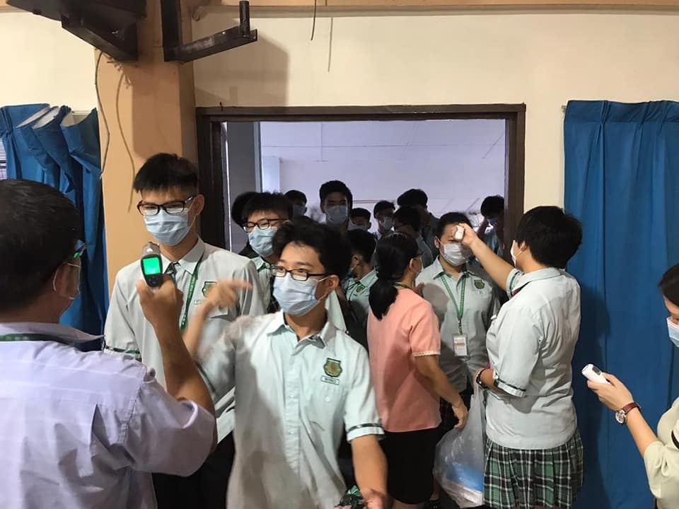 行政老师正为教职员、孩子们进行体温检查。